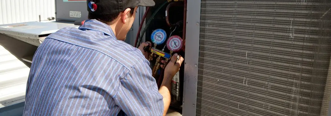 HVAC technician servicing a condenser unit in Tea